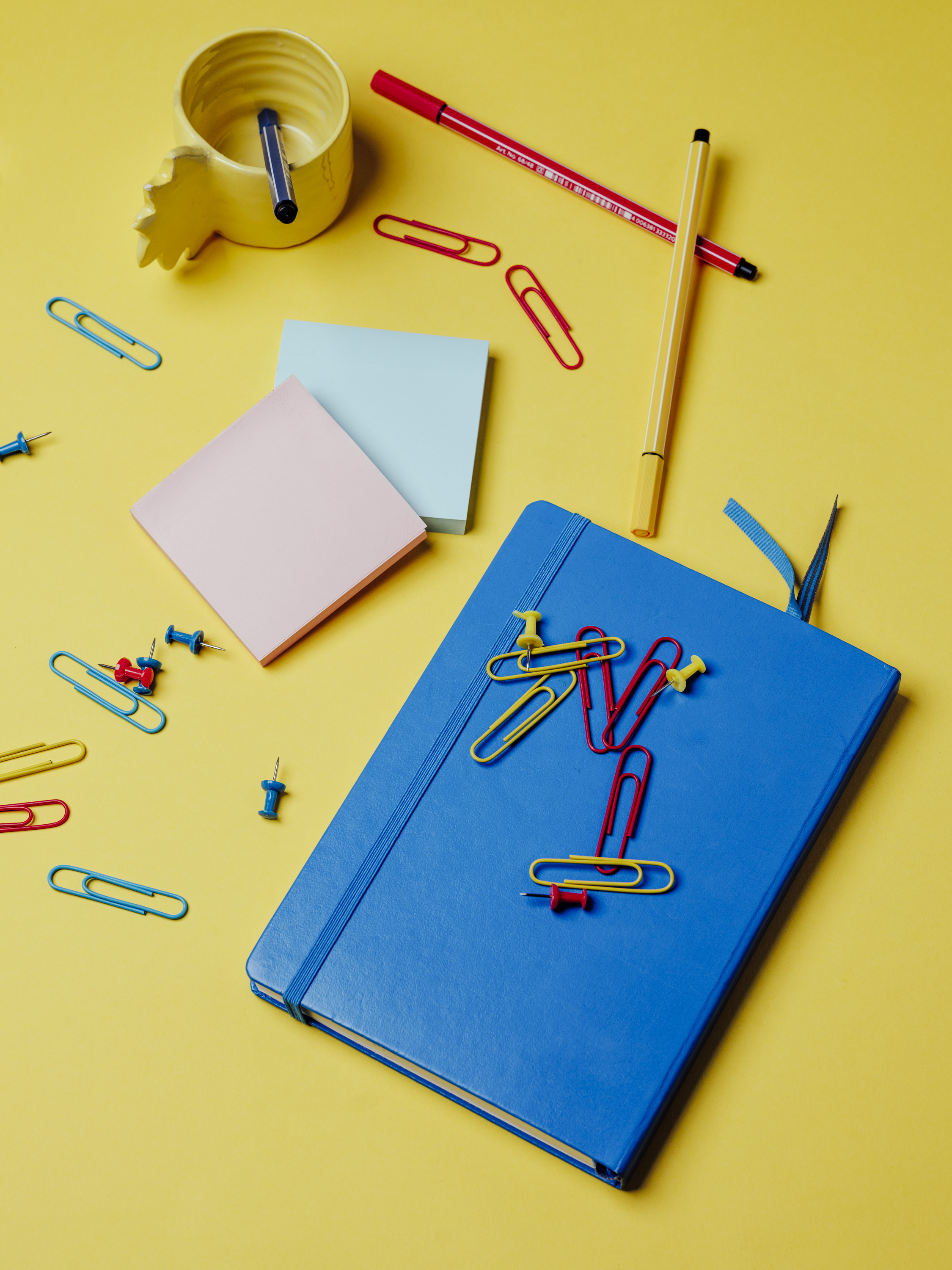 matériel scolaire sur fond jaune cahiers, punaises, blocs